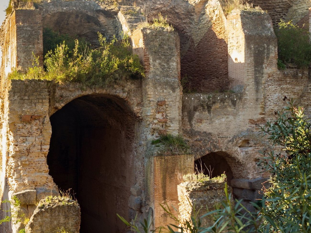 Il parco archeologico delle Terme di Baia al tramonto — le imponenti pareti e gli archi in laterizio del complesso termale imperiale romano sopra il golfo